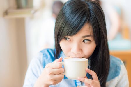 Happy asian young woman sitting in vintage cafe with cup of coffee, Vintage woman coffeeの写真素材