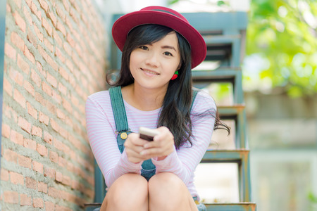 City lifestyle stylish hipster woman using phone texting on smartphone. business woman in cafe outdoorの写真素材