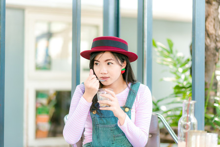 happy young asian woman with coffee cup sitting on benchの写真素材
