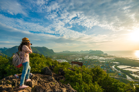 Hiker woman with camera enjoy the view at sunrise mountain peak cliffの写真素材