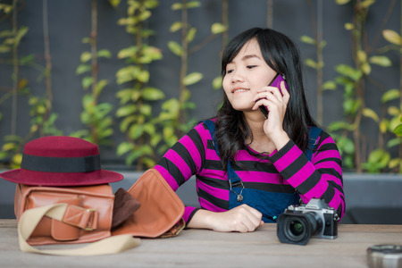 Young photographer woman using on mobile phone in cafe outdoors city urban background.の写真素材