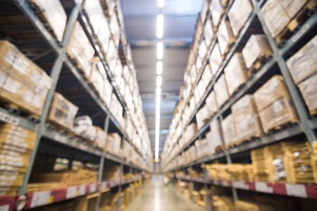 Abstract blurred boxes on rows of shelves in big modern warehouse background