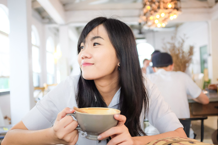 Asian young woman hold coffee cup in a coffee shopの写真素材