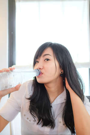 Portrait of young beautiful asian woman drinking water at restaurantの写真素材