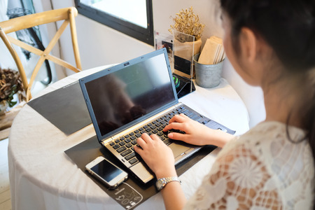 Close up of typing female hands on laptop and cellphoneの写真素材