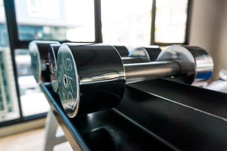 Dumb bells lined up in fitness room,  modern sports club.