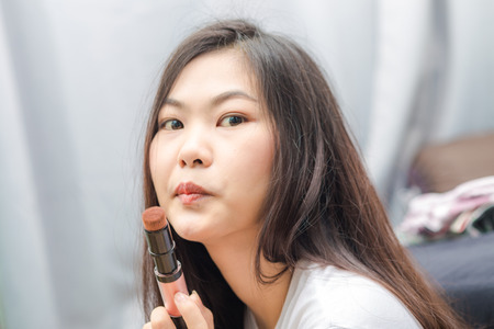 Young asian woman applying cosmetic paint brush in bedroomの写真素材