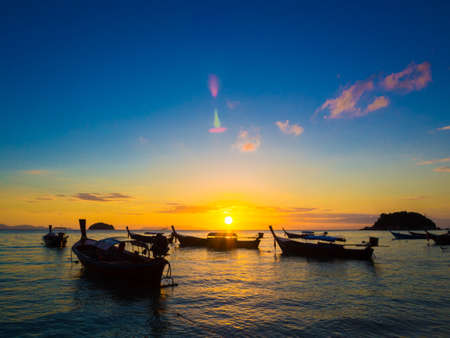 Tropical Island sunset with beach and boat in silhouette