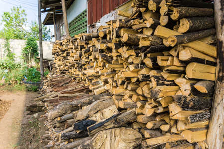 Background of firewood near house, dry chopped firewood logs in a pileの写真素材