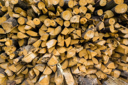 Background of firewood near house, dry chopped firewood logs in a pileの写真素材