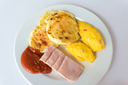 Breakfast with scrambled eggs, toasts, and bacon on white tableの写真素材