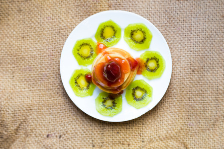 Pancakes with butter and fruit on white dishの写真素材