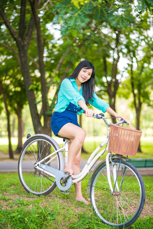 Beautiful young smiling woman on bike in green parkの写真素材