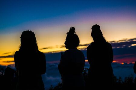 Tourist enjoying take photo on peak of mountain sunrise silhouette, Thailandの写真素材
