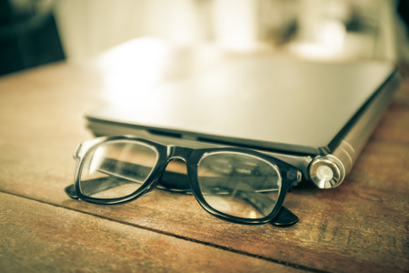 Glasses with laptop Workspace on wood table vintage filterの写真素材