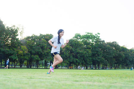 Young fitness woman running at park on green grass, Workout women