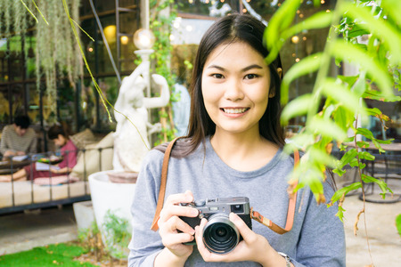 Cute hipster young female photographer with camera outdoors at the parkの写真素材
