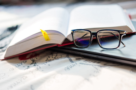 Books with a pair of glasses and computer laptop on bedroom, Technology learningの写真素材