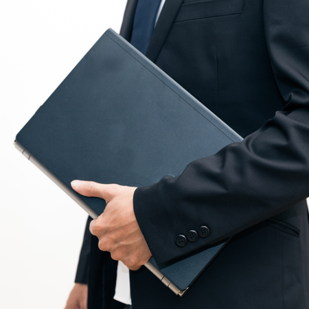 Business asian man wear black suit hand holding with modern laptop on white backgroundの写真素材