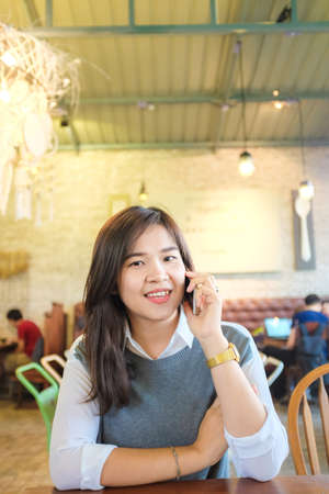 Happy asian woman talking on cellphone in hipster cafe, Women rest in cafeの写真素材