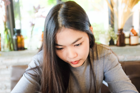 Charming asian woman with beautiful smile reading off touch phone and reading good news on mobile phoneの写真素材