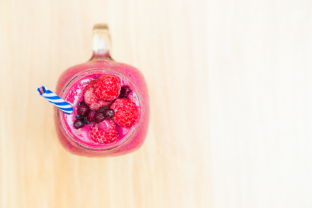 Jar of smoothies with strawberries rasberry and blueberry on wooden table close up from aboveの写真素材
