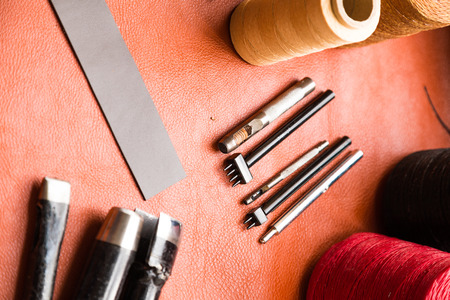 Leather crafting tools make camera strap still life on green work space board, Leather product