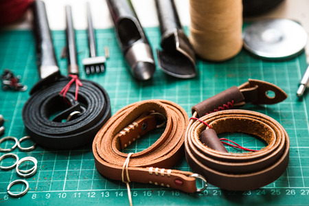 Leather crafting tools make camera strap still life on green work space board, Leather product