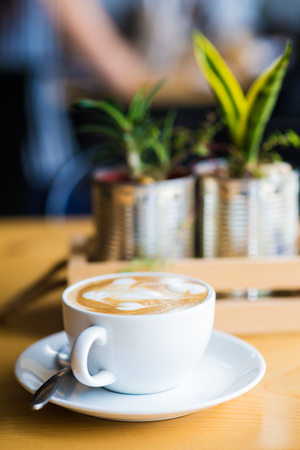 Coffee cup and flower decor on wooden background in coffee shopの写真素材