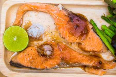 Delicious grilled of fresh salmon fillet with aromatic herbs on wood plateの写真素材