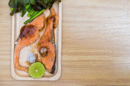 Delicious grilled of fresh salmon fillet with aromatic herbs on wood plateの写真素材