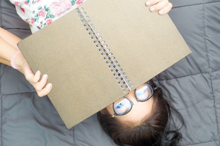 Glasses woman lying in bed while reading a book, Education every where