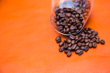 Coffee beans out from glass on leather background close upの写真素材