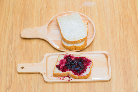 Slices of bread with blackcurrant jam for breakfast on wooden table