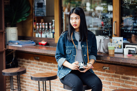 Portrait of asian beautiful young hipster woman with mirrorless camera in cafe, Retro lifestyleの写真素材