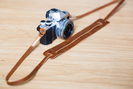 Leather craft camera strap with mirrorless camera on wood tableの写真素材