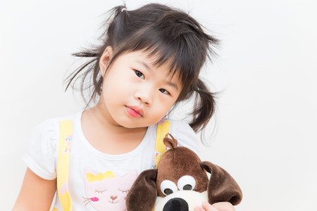 Little asian cute girl holding large dog doll on white