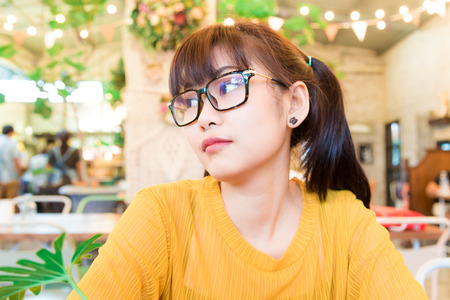 Asian hipster nerd glasses women sitting at the coffee shop Cafe Background.の写真素材
