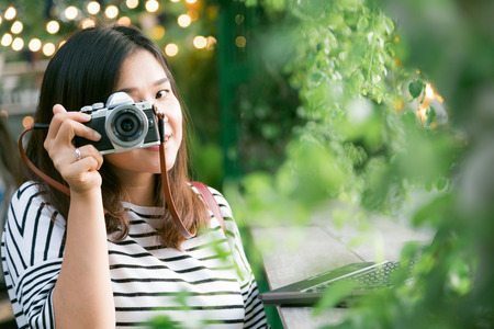 Young asian woman making photos with vintage film camera at summer green park outdoor.の写真素材
