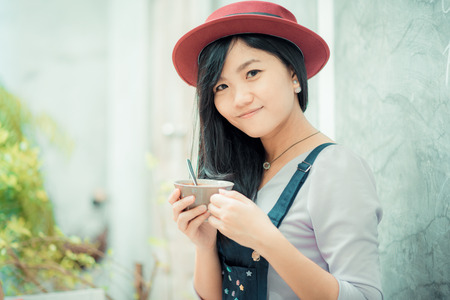 Asian cute women holding coffee cup on  art wall, Women leans against a concrete wall.の写真素材