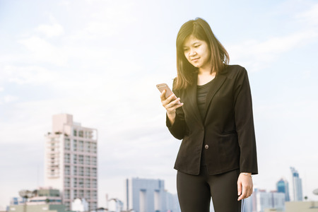 Happy Asian Businesswoman talking on smart phone with building background.の写真素材