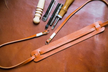 Genuine leather camera strap handmade with meatal tool on leather  background