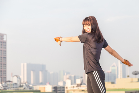 Asian female in sports clothing make body stretching before workout on building background.のeditorial素材