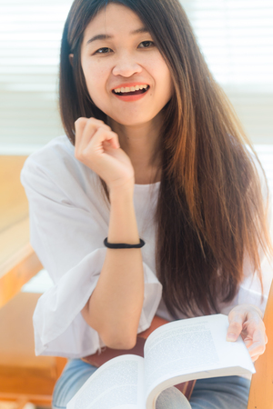 Portrait of a young attractive asian woman at the library sitting to reading a book. Education conceptのeditorial素材