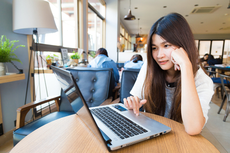 Beautiful hipster student woman using laptop and drinking coffee at cafeのeditorial素材