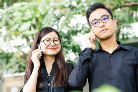 Businesman and woman use cellphone for business talking in park, Co businessのeditorial素材