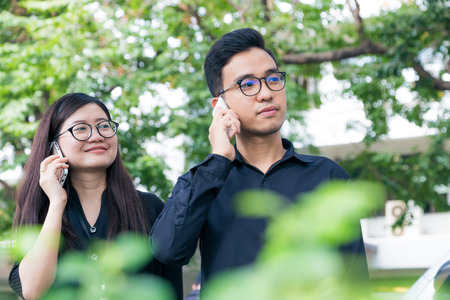 Businesman and woman use cellphone for business talking in park, Co businessのeditorial素材