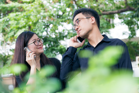 Businesman and woman use cellphone for business talking in park, Co businessのeditorial素材