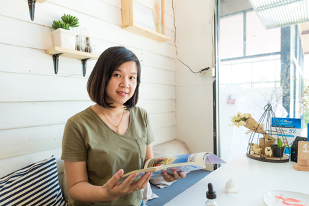 Young student woman at cafe drinking coffee and reading book, Education business conceptの写真素材
