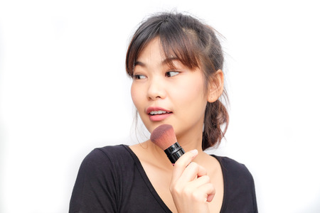Beautiful young asian woman applying cosmetic paint brush, Perfect makeup isolated on whiteの写真素材